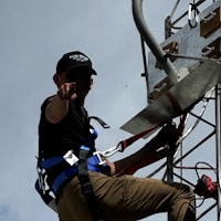 a man is climbing a tower with a rope attached to it